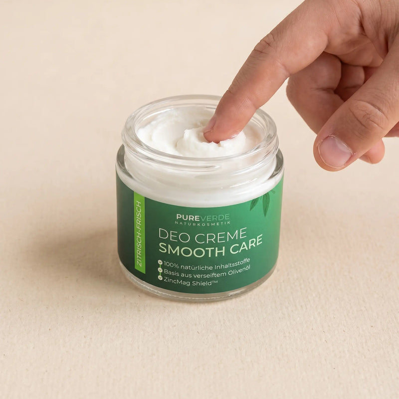Ein Finger entnimmt Deo-Creme aus dem geöffneten Tiegel.
